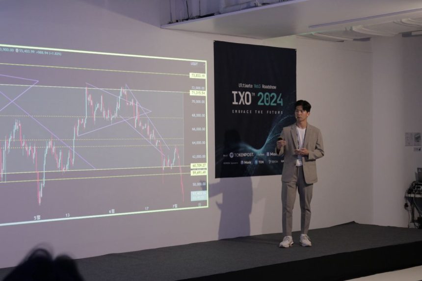 IXO 2024 무대에서 비트코인 차트를 띄우고 연설 중인 트레이더 이재민